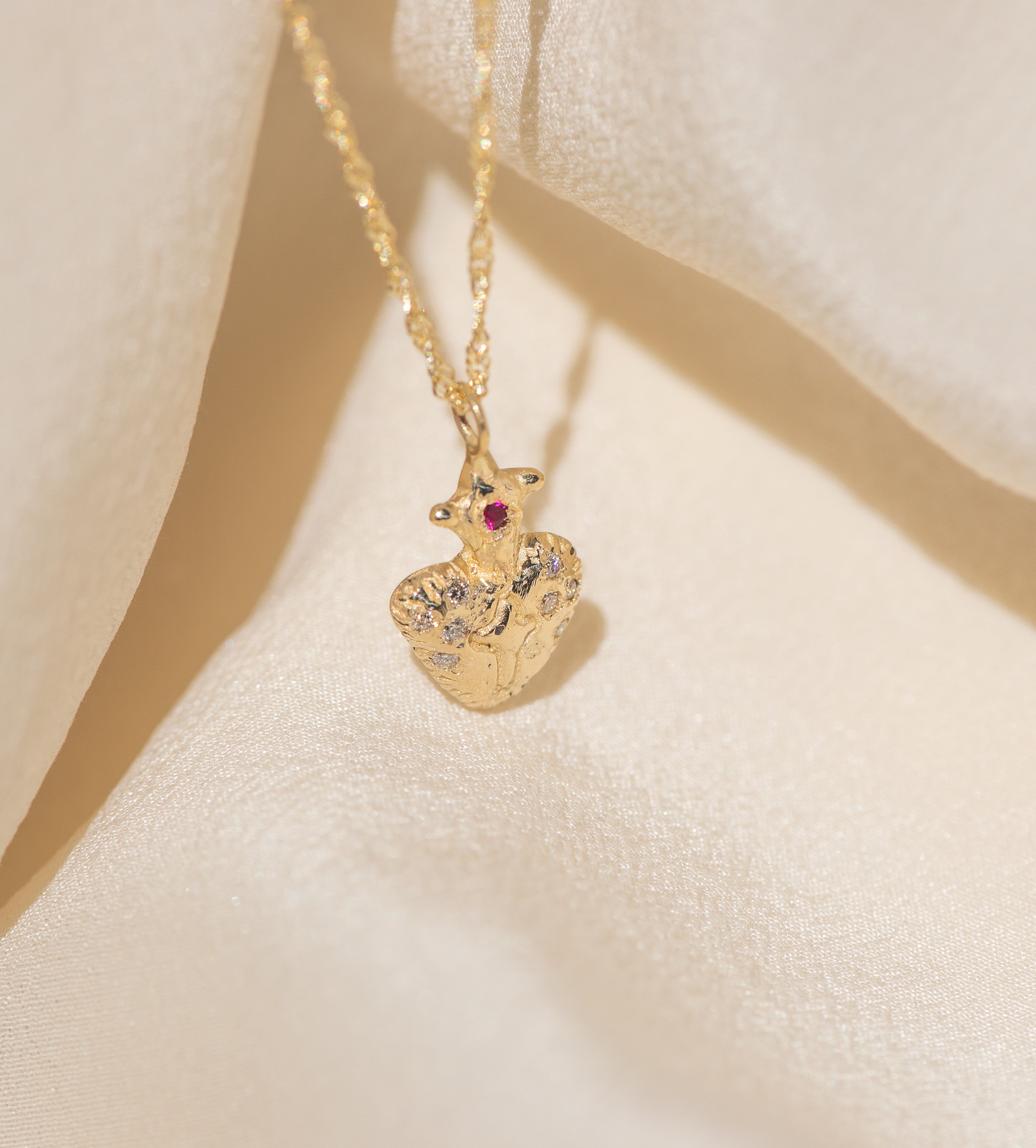 Gold necklace with a detailed pendant on a beige fabric background