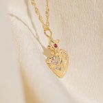 Gold necklace with a heart-shaped pendant on a beige background