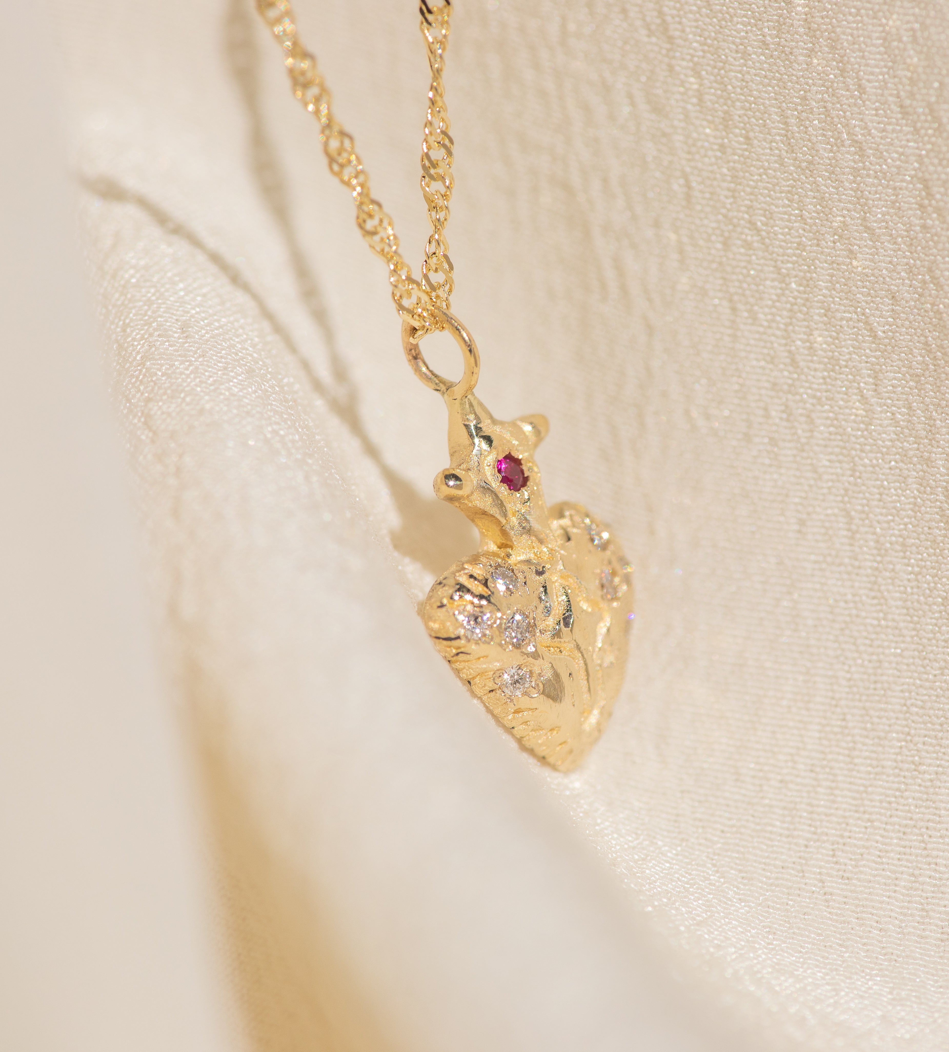 Gold necklace with a heart-shaped pendant on a beige background