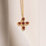 Gold necklace with a cross pendant featuring garnet gemstones
