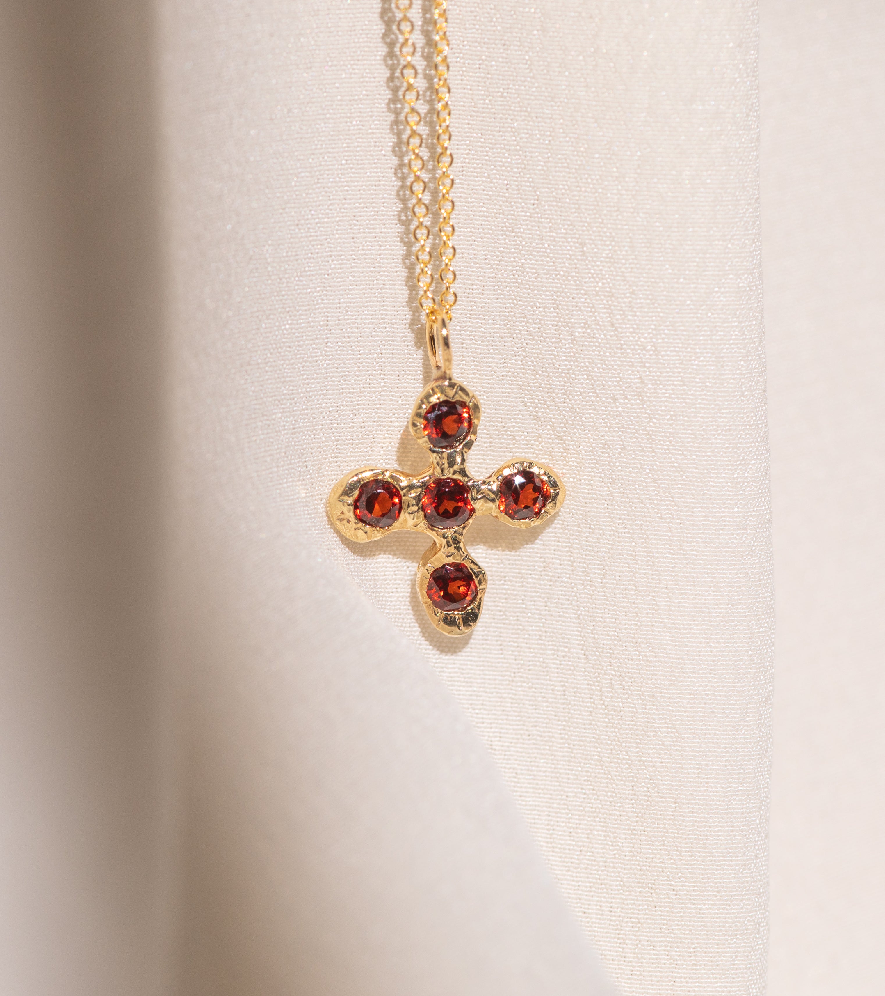 Gold necklace with a cross pendant featuring garnet gemstones