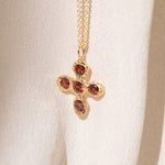 Gold necklace with a cross pendant featuring garnet gemstones
