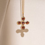 Gold necklace with a cross pendant featuring garnet gemstones