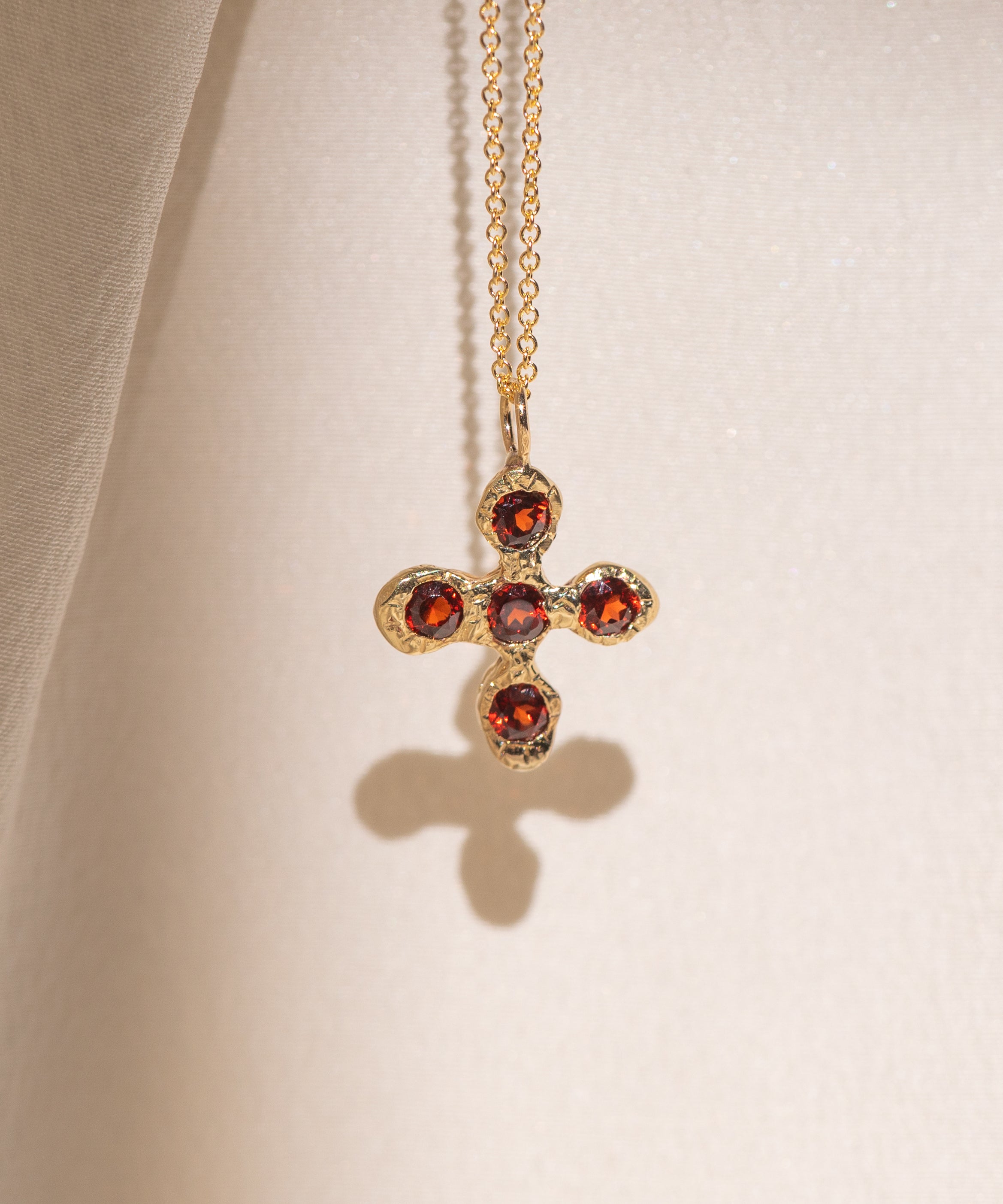 Gold necklace with a cross pendant featuring garnet gemstones