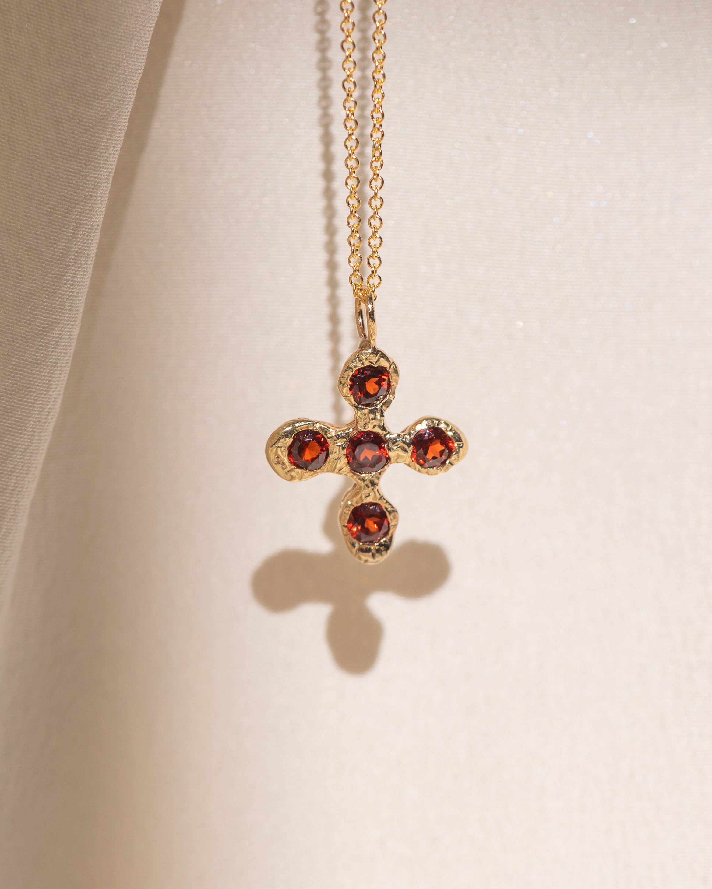 Gold necklace with a cross pendant featuring garnet gemstones