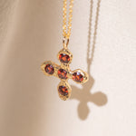 Gold necklace with a cross pendant featuring garnet gemstones