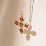 Gold necklace with a cross pendant featuring garnet gemstones