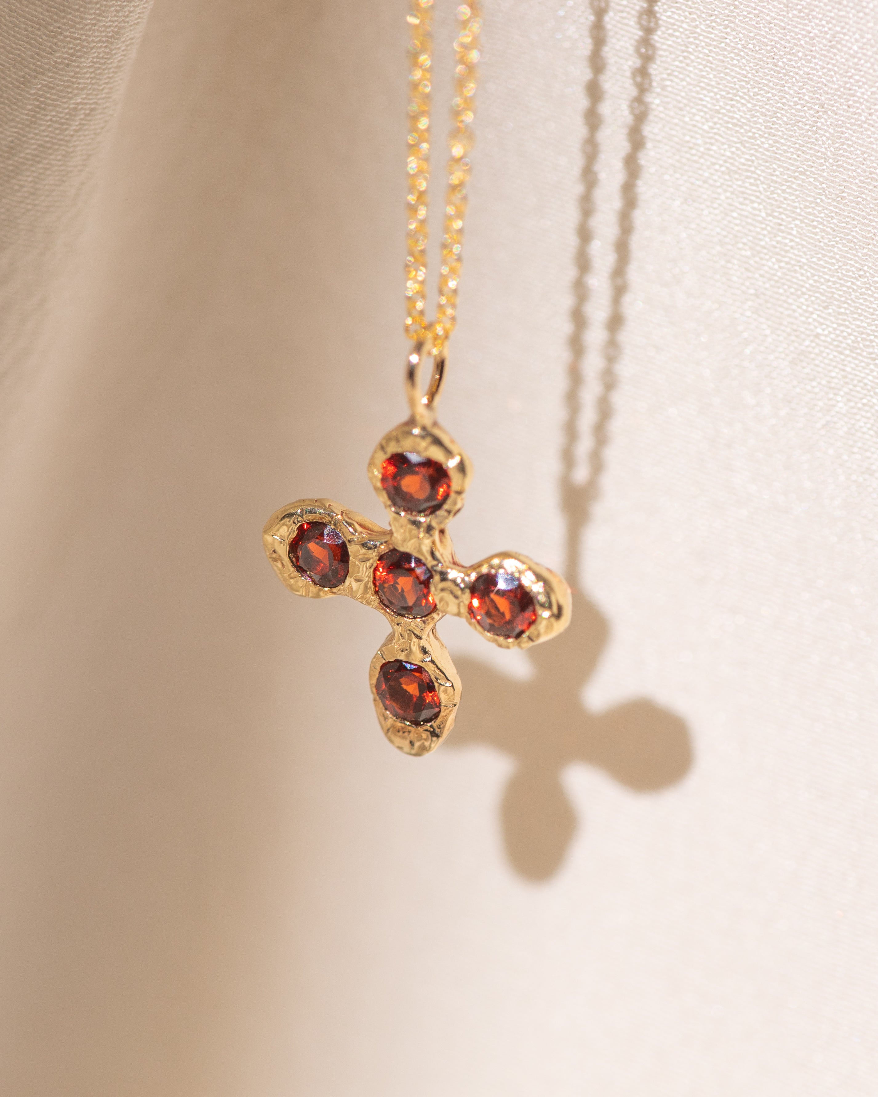 Gold necklace with a cross pendant featuring garnet gemstones