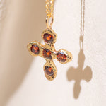 Gold necklace with a cross pendant featuring garnet gemstones