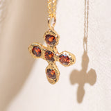 Gold necklace with a cross pendant featuring garnet gemstones