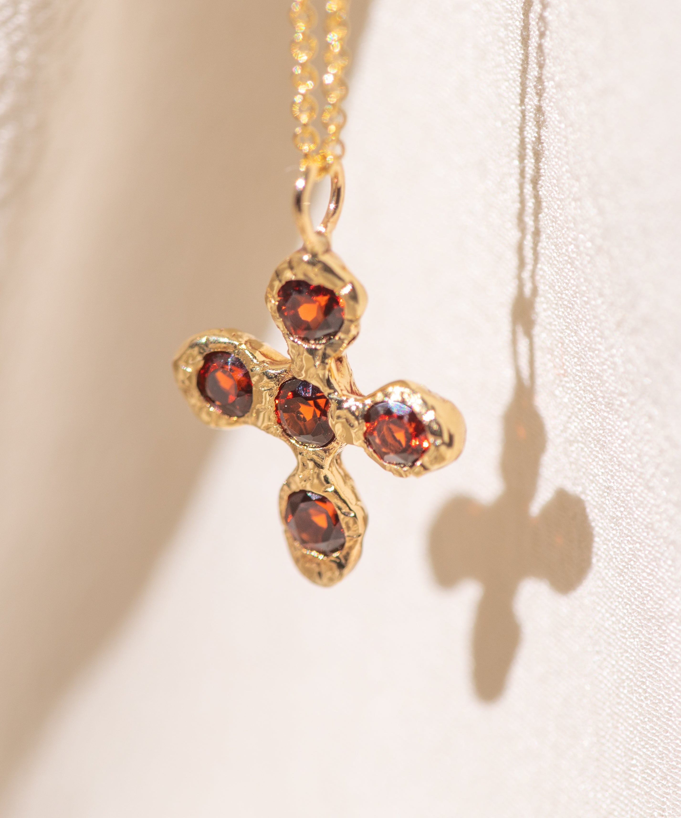 Gold necklace with a cross pendant featuring garnet gemstones