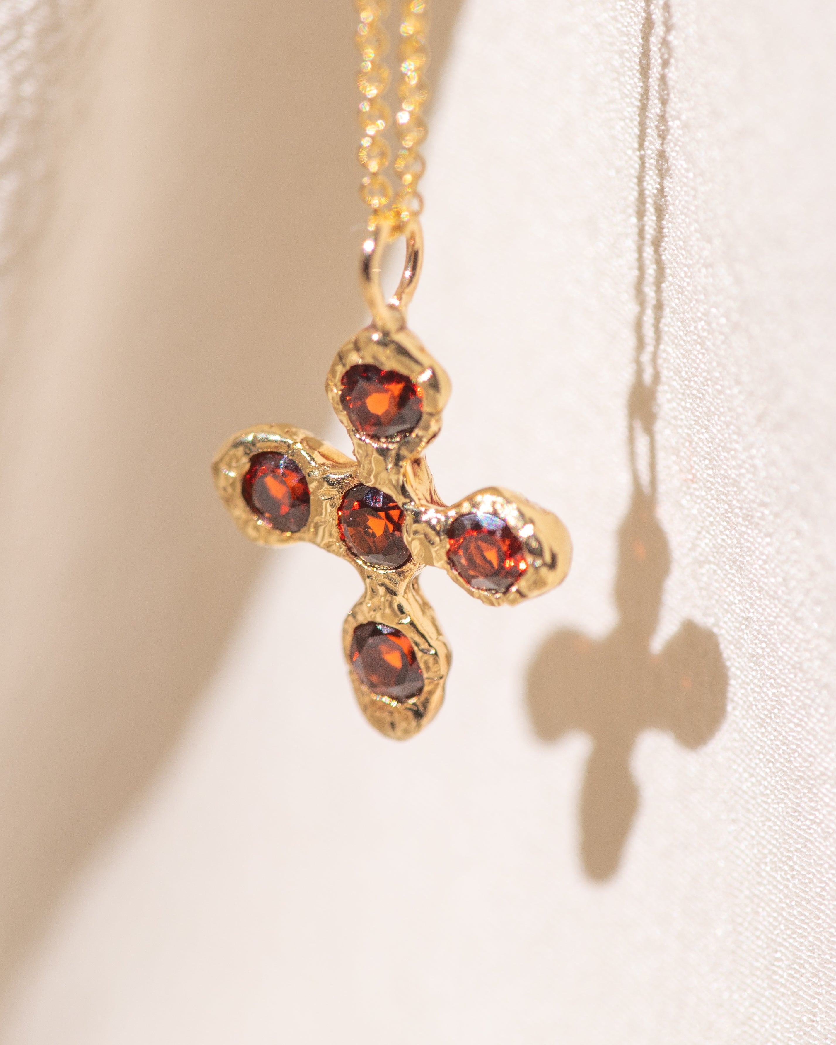 Gold necklace with a cross pendant featuring garnet gemstones