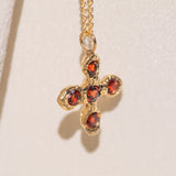 Gold necklace with a cross pendant featuring garnet gemstones