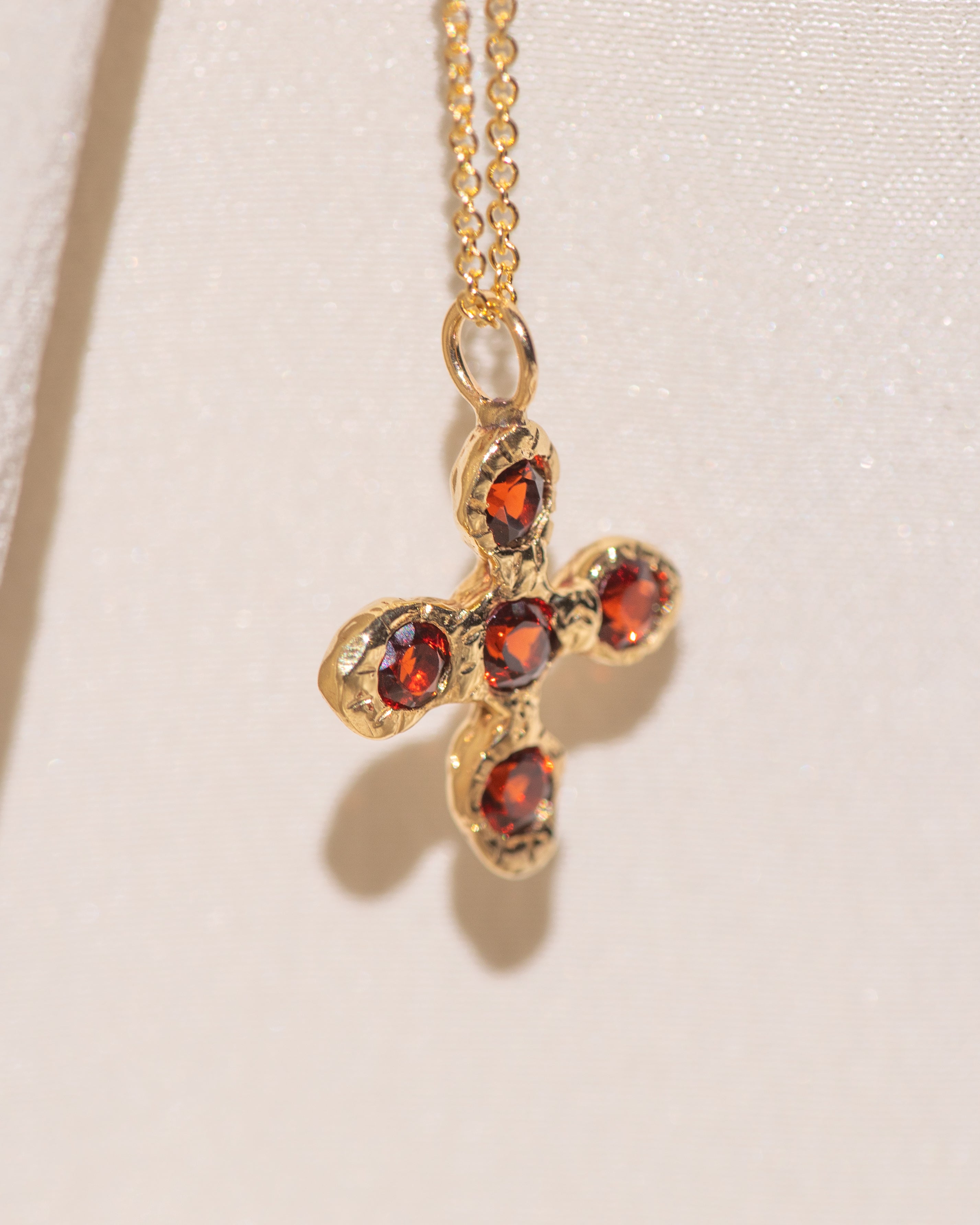 Gold necklace with a cross pendant featuring garnet gemstones