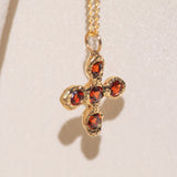 Gold necklace with a cross pendant featuring garnet gemstones