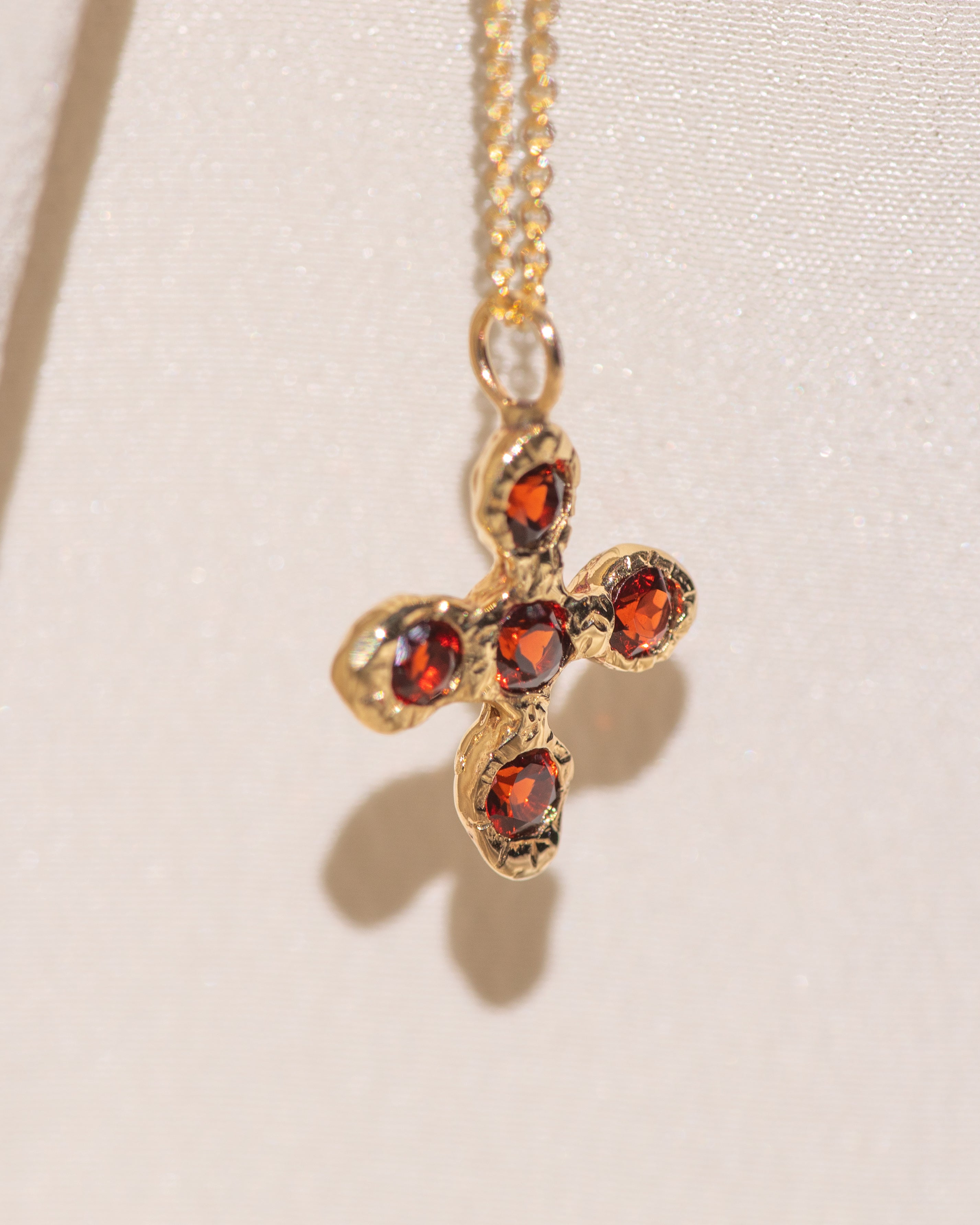 Gold necklace with a cross pendant featuring garnet gemstones
