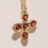 Gold necklace with a cross pendant featuring garnet gemstones