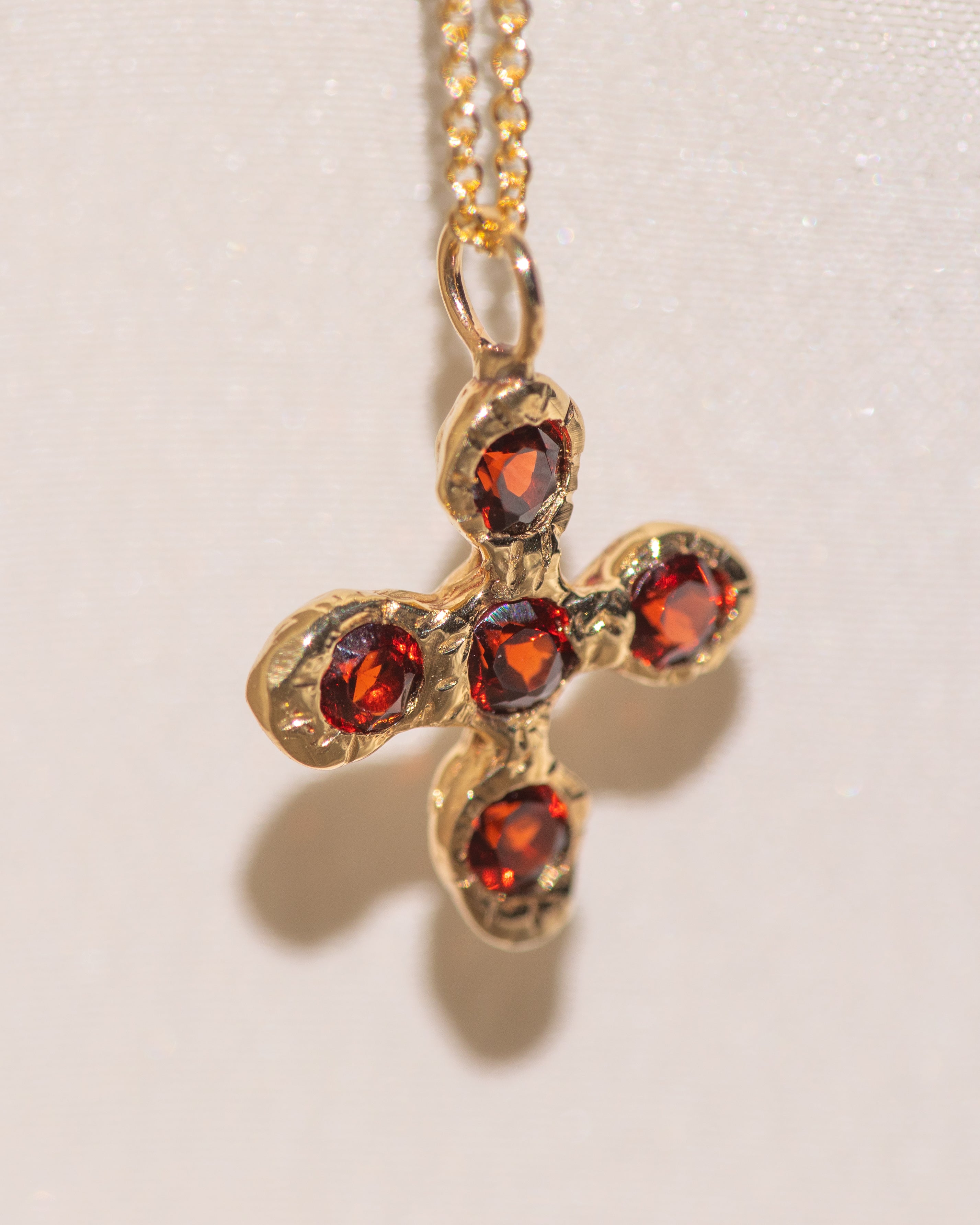 Gold necklace with a cross pendant featuring garnet gemstones