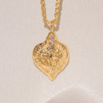 Gold heart-shaped medallion necklace featuring a white diamond and a dove on rope chain