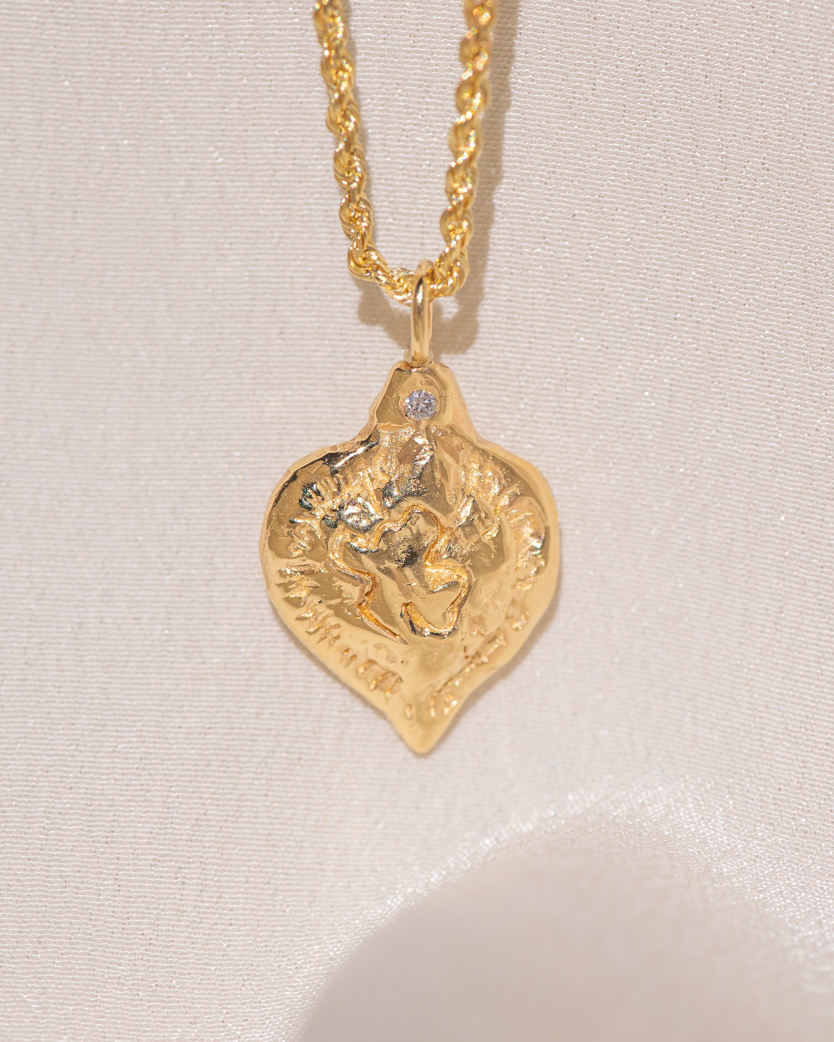 Gold heart-shaped medallion necklace featuring a white diamond and a dove on rope chain