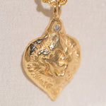 Gold heart-shaped medallion necklace featuring a white diamond and a dove