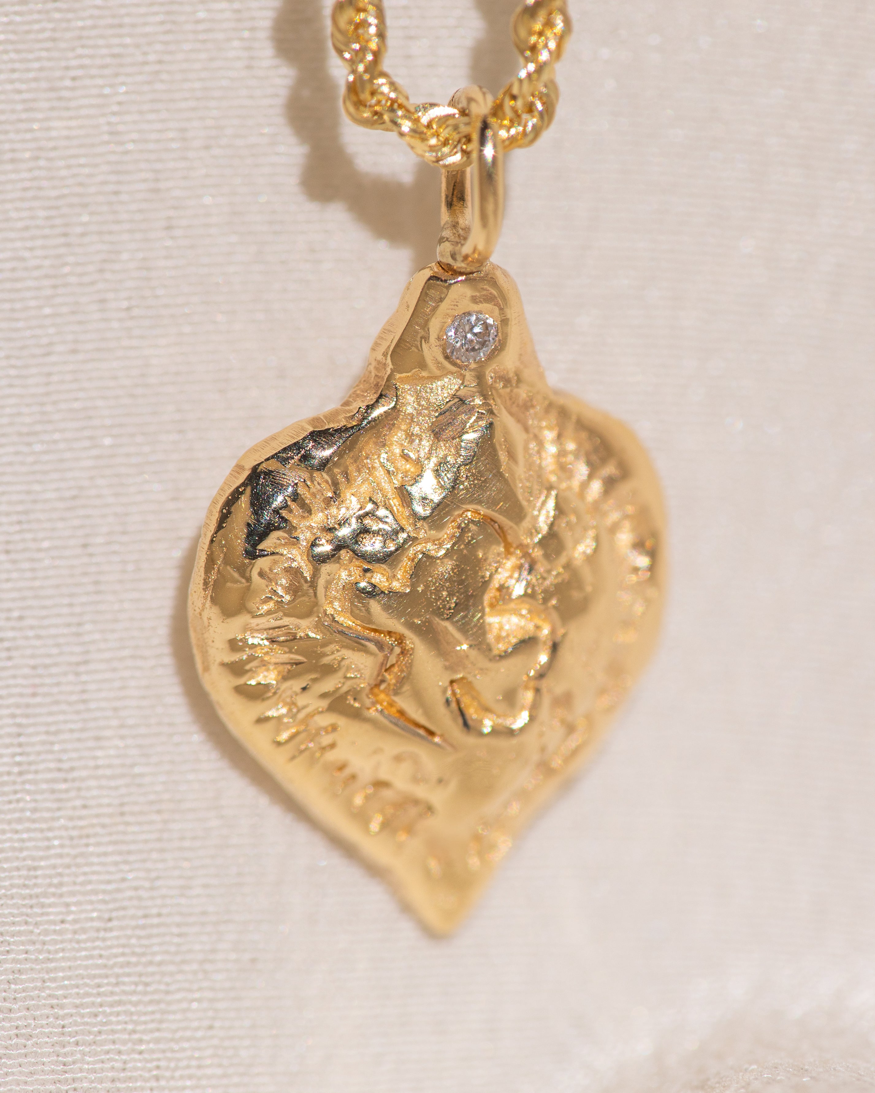 Gold heart-shaped medallion necklace featuring a white diamond and a dove