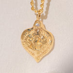 Gold heart-shaped medallion necklace featuring a white diamond and a dove