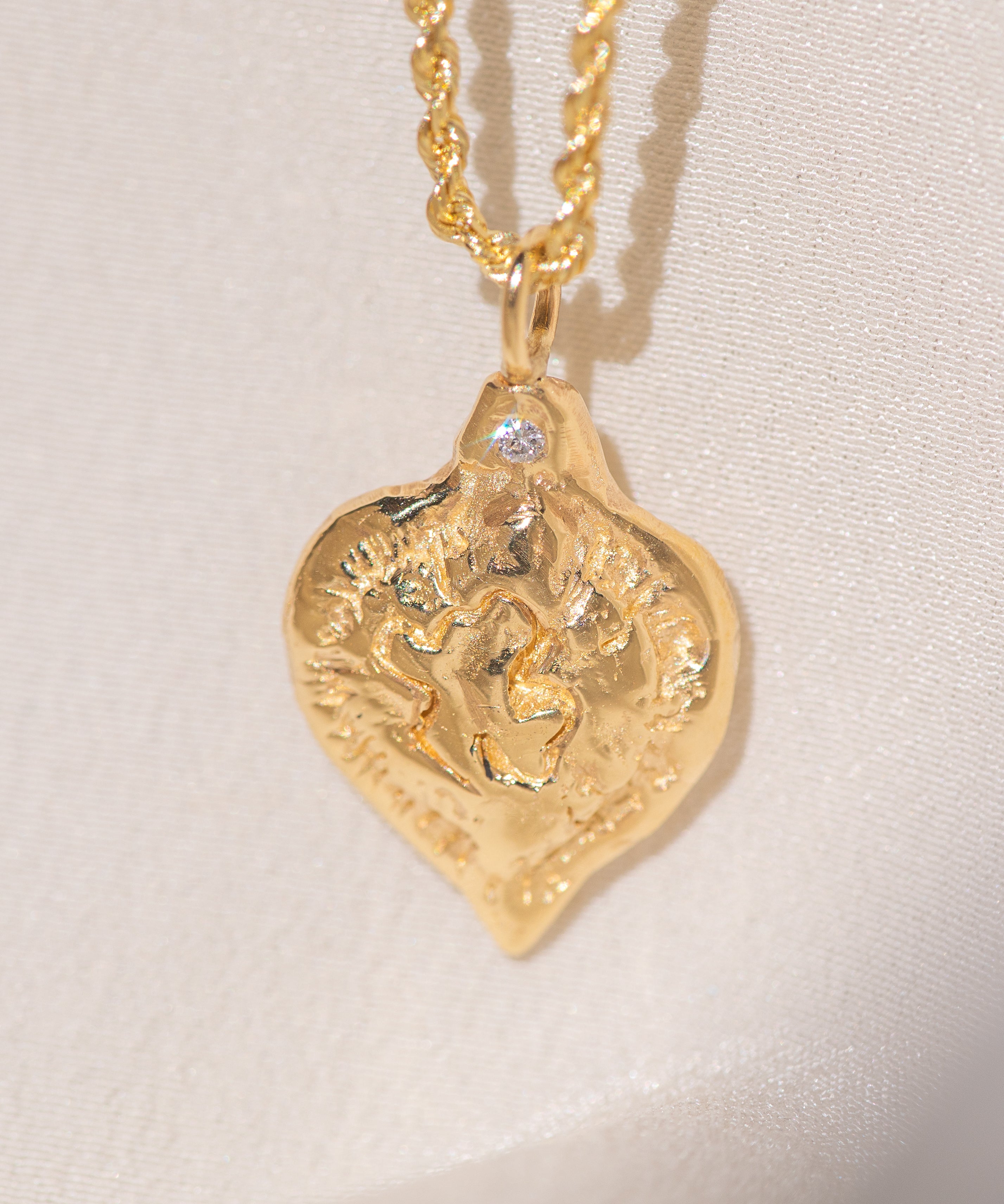 Gold heart-shaped medallion necklace featuring a white diamond and a dove