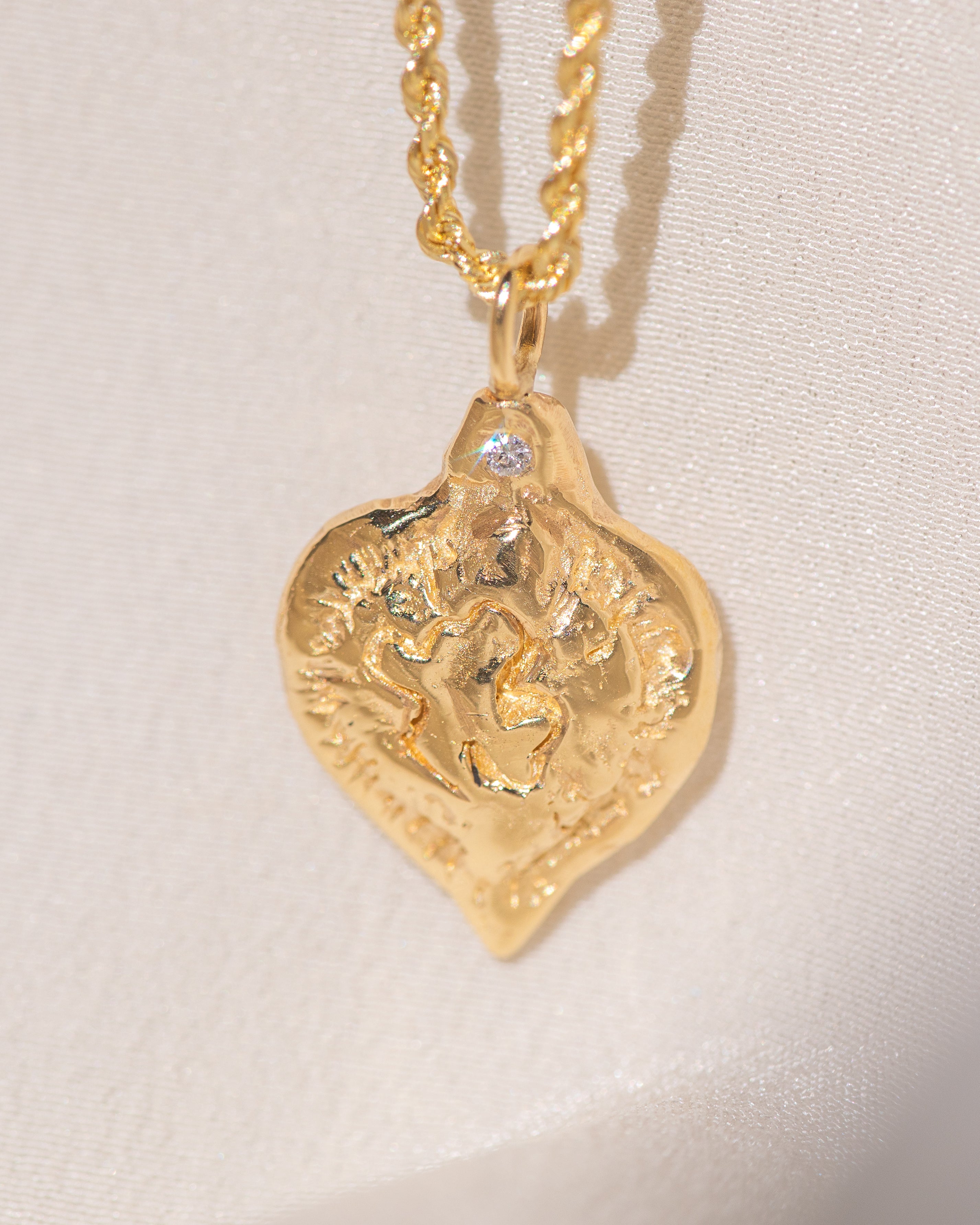 Gold heart-shaped medallion necklace featuring a white diamond and a dove