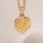 Gold heart-shaped medallion necklace featuring hand carved "liberty" in the back