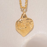 Gold heart-shaped medallion necklace featuring hand carved "liberty" in the back