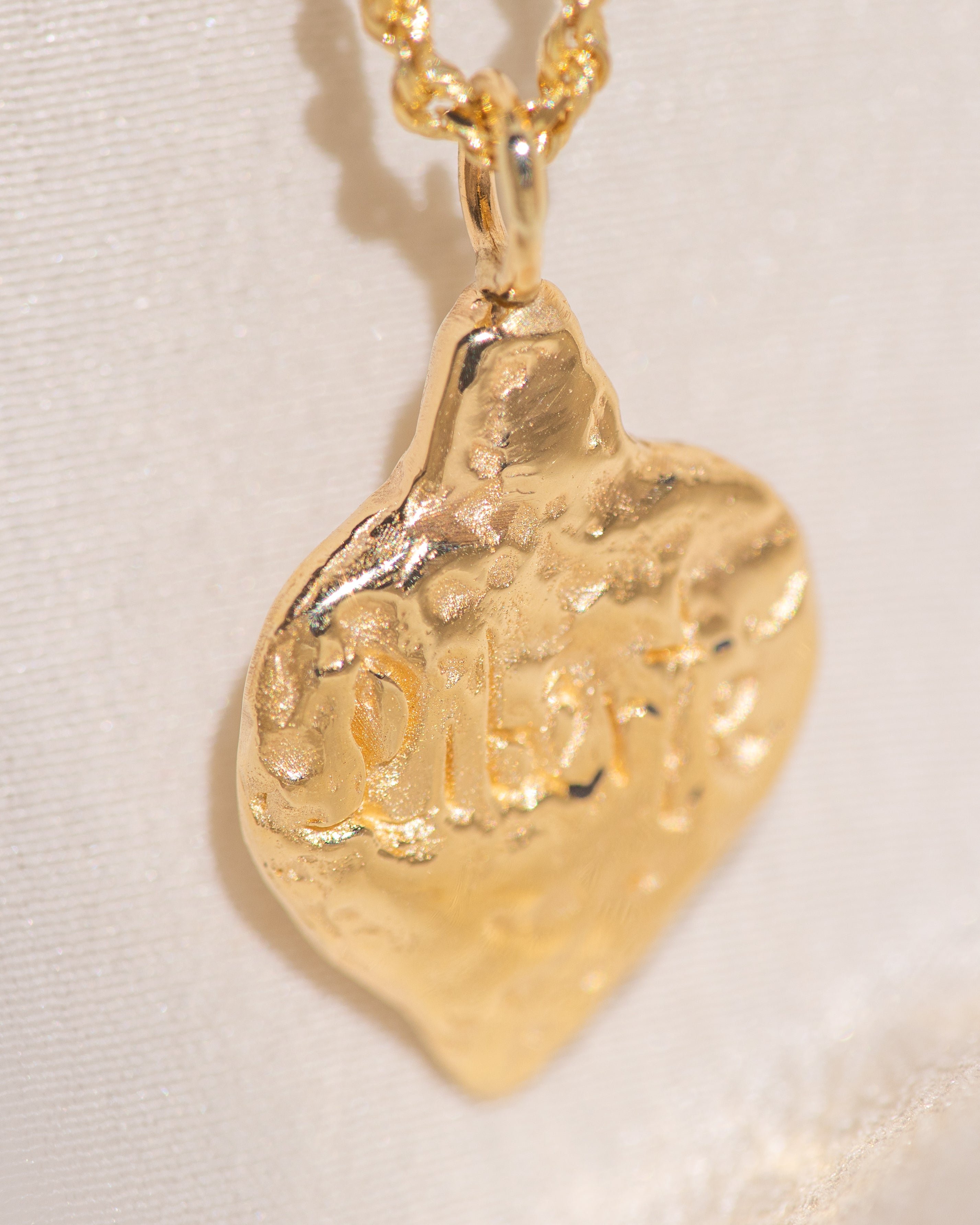 Gold pendant necklace on a light beige background