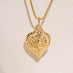 Gold heart-shaped medallion necklace featuring a white diamond and a dove on box chain