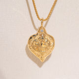 Gold heart-shaped medallion necklace featuring a white diamond and a dove on box chain