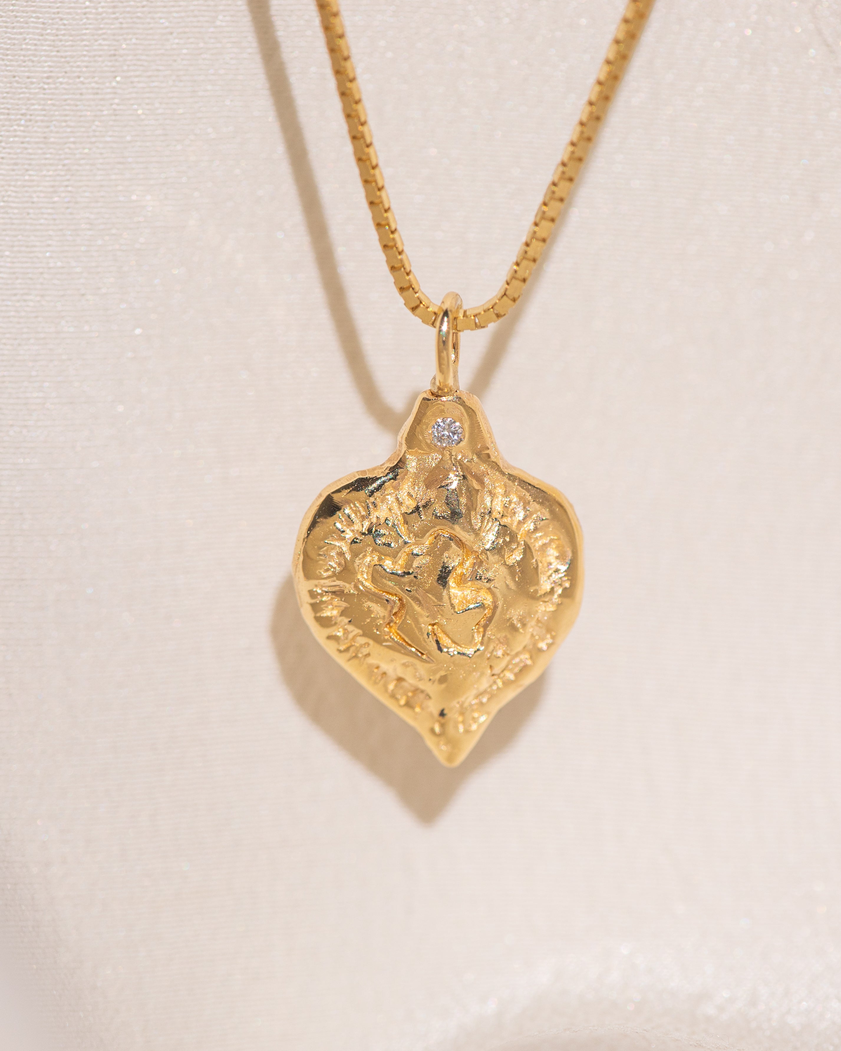Gold heart-shaped medallion necklace featuring a white diamond and a dove on box chain