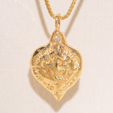 Gold heart-shaped medallion necklace featuring a white diamond and a dove