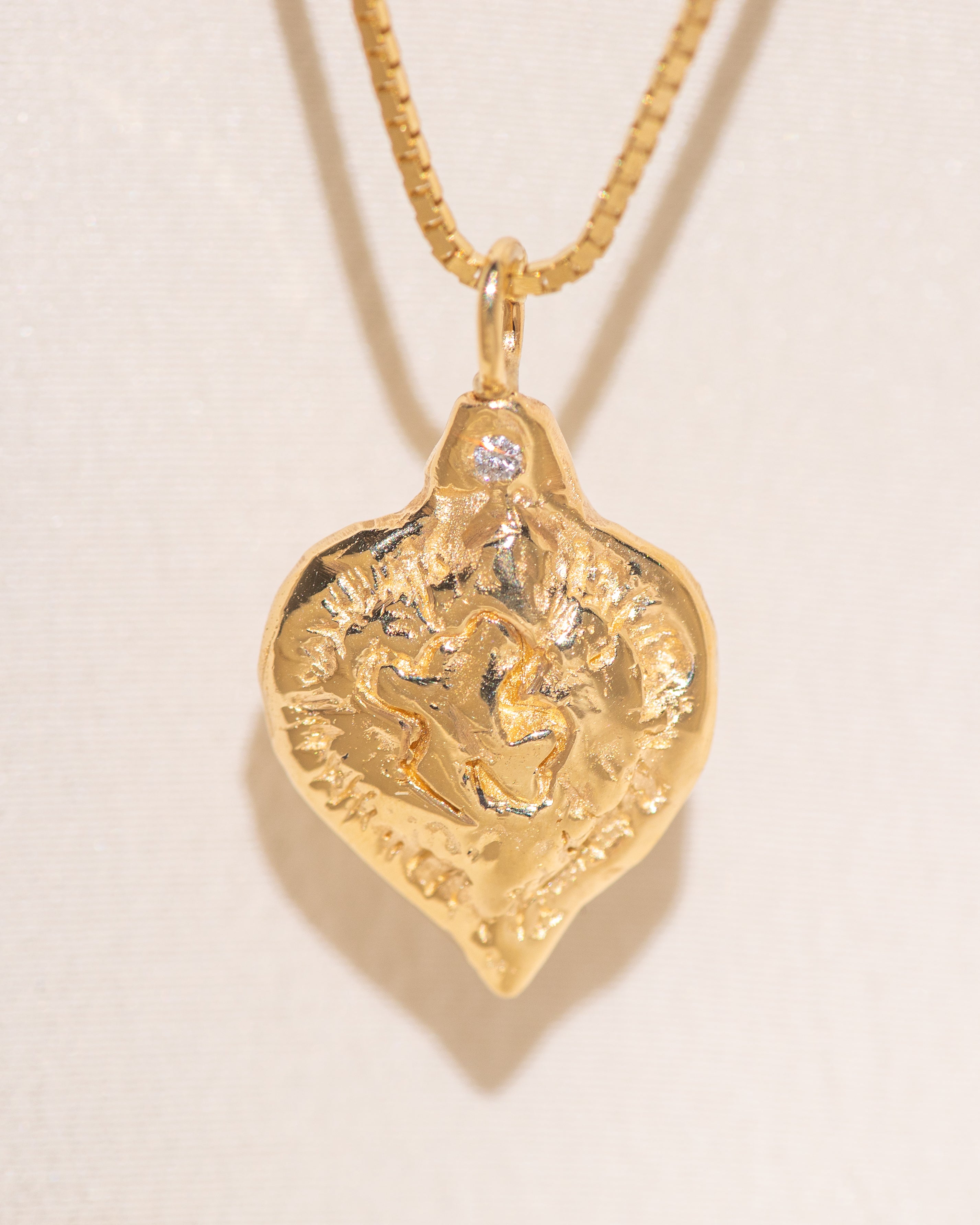 Gold heart-shaped medallion necklace featuring a white diamond and a dove