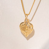 Gold heart-shaped medallion necklace featuring a white diamond and a dove