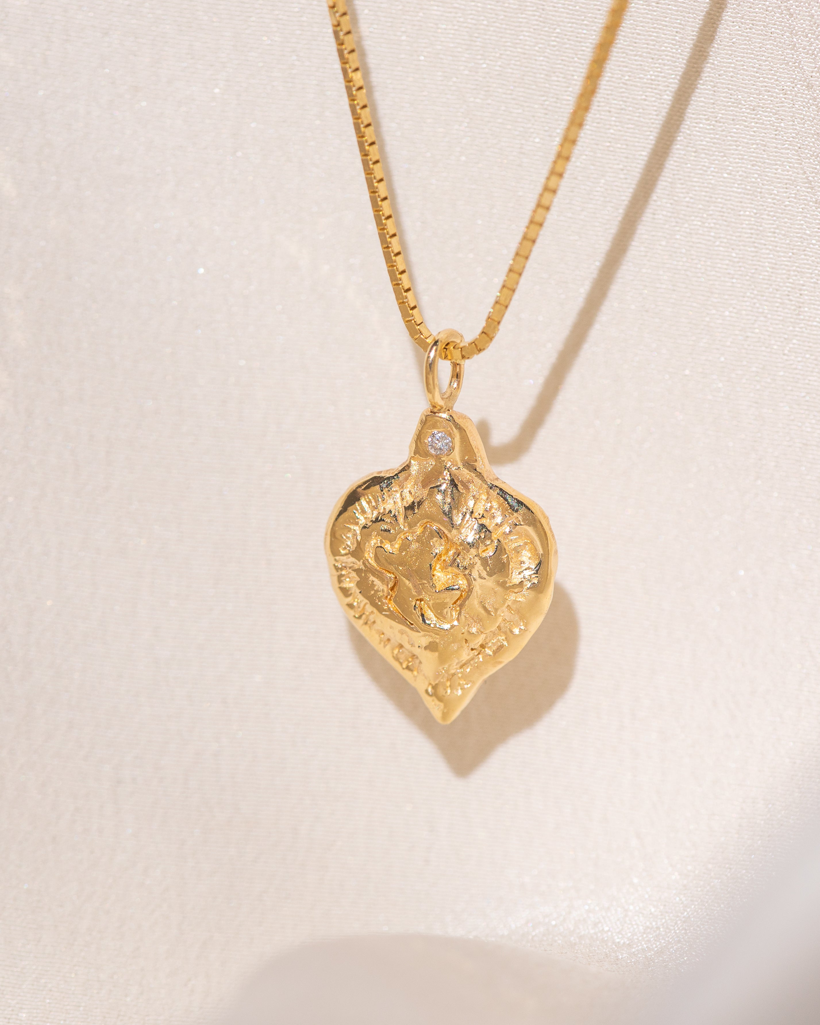 Gold heart-shaped medallion necklace featuring a white diamond and a dove